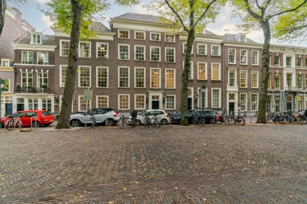 Rijtje monumentale panden aan het Lange Voorhout in Den Haag met geparkeerde auto’s en fietsen op de voorgrond.